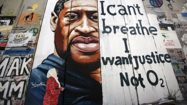 A woman looks at a mural showing the face of George Floyd, an unarmed black man who died after a white policeman knelt on his neck during an arrest in the US, painted on a section of Israel's controversial separation barrier in the city of Bethlehem in the occupied West Bank on June 10, 2020, with text reading "I can't breathe, I want justice not O2". Musa Al SHAER / AFP