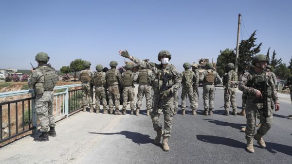 Turkish soldiers stand guard on a bridge overlooking a section of the M4 highway, which links the northern Syrian provinces of Aleppo and Latakia, during a joint Russian-Turkish military convoy near Ariha in Syria's rebel-held northwestern Idlib province, on June 10, 2020. OMAR HAJ KADOUR / AFP