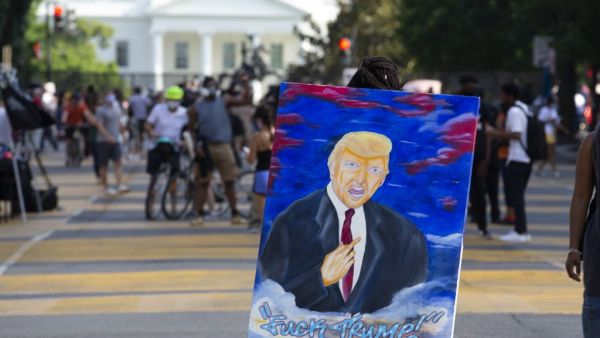 A demonstrator walks holding an anti-Trump painting on Black Lives Matter Plaza near the White House, to protest police brutality and racism, on June 10, 2020 in Washington, DC. Demonstrations are being held across the US following the death of George Floyd on May 25, 2020, while being arrested in Minneapolis, Minnesota. Jose Luis Magana / AFP