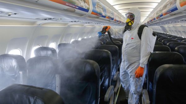 An Israeli worker in full hazmat suit sprays disinfectant in the cabin of an Israir Airlines Airbus A320 airplane, at the Ben Gurion International Airport near the central Israeli city of Tel Aviv, on June 14, 2020, amid the novel coronavirus pandemic. GIL COHEN-MAGEN / AFP
