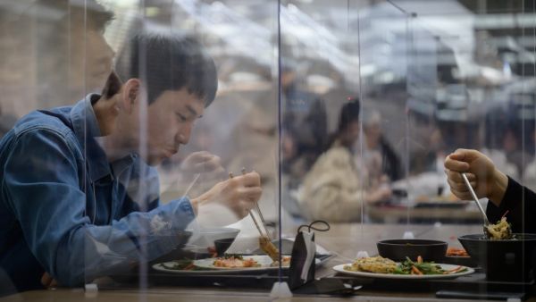 In this file photo taken on April 9, 2020 employees sit behind protective screens as part of preventative measures against the COVID-19 novel coronavirus, as they eat in a cafeteria at the offices of Hyundai Card credit card company in Seoul. Ed JONES / AFP