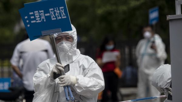 Medical staff in full protective gear carry signs to assist people who live near or who have visited the Xinfadi Market, a wholesale food market where a new COVID-19 coronavirus cluster has emerged, as they arrive for testing in Beijing on June 17, 2020. Beijing's airports cancelled two-thirds of all flights and schools in the Chinese capital were closed again on June 17 as authorities rushed to contain a new coronavirus outbreak linked to the Xinfadi wholesale food market. NOEL CELIS / AFP