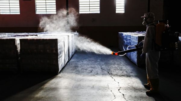 An employee disinfects supplies at a municipal warehouse in Curitiba, Brazil, on June 19, 2020. DANIEL CASTELLANO / AFP