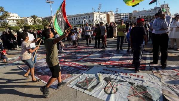 Children wave flags of Libya and the Amazigh as they walk on protest signs showing "X" marks on the faces of (R to L) French President Emmanuel Macron, Egyptian President Abdelfattah el-Sisi, and Abu Dhabi's Crown Prince Sheikh Mohammed bin Zayed Al Nahyan, during a demonstration in the Martyrs' Square. (AFP)