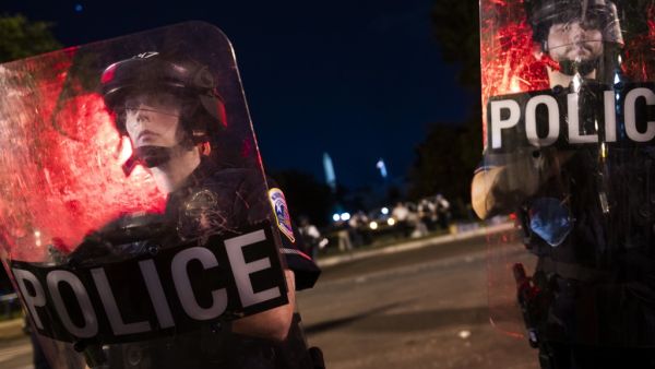 Policemen look through their shields as they and others members of their team are keeping protesters from entering Lafayette Park near the White House, in Washington, DC on June 22, 2020. A crowd of protestors tried to topple the statue of former US president General Andrew Jackson near the White House in the evening of June 22 as police responded with pepper spray to break up new demonstrations that erupted in Washington. ROBERTO SCHMIDT / AFP