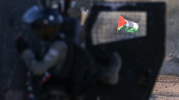 The Palestinian national flag is seen through the window of an Israeli military vehicle amid clashes following a rally against Israel's West Bank annexation plans, in the Jordan Valley village of Fasayil on June 24, 2020. JAAFAR ASHTIYEH / AFP