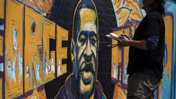 A group of artists paint a mural of George Floyd on the wall outside of Cup Foods, where Floyd was killed in police custody, on May 28, 2020 in Minneapolis, Minnesota. People have gathered at the site since Floyd was killed earlier this week. Stephen Maturen/Getty Images/AFP Stephen Maturen / GETTY IMAGES NORTH AMERICA / Getty Images via AFP