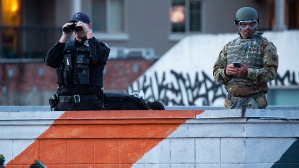 Personnel from the Seattle Police Department and the Washington National Guard keep an eye on demonstrators from a rooftop near the Seattle Police Departments East Precinct on June 6, 2020 in Seattle, Washington. This is the 12th day of protests since George Floyd died in Minneapolis police custody on May 25. David Ryder/Getty Images/AFP David Ryder / GETTY IMAGES NORTH AMERICA / Getty Images via AFP
