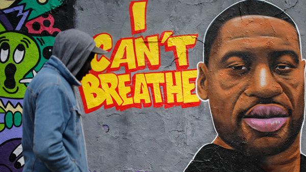 A man walks past a graffiti on a wall depicting a portrait of George Floyd, a black man who died in Minneapolis after a white policeman kneeled on his neck for several minutes, at Mauer Park in Berlin's Prenzlauer Berg district on May 30, 2020. (Photo by David GANNON / AFP)