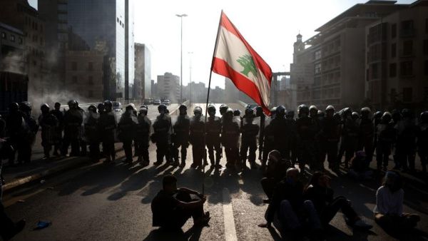 Lebanese protesters wave the national flag in front of riot police in Beirut /AFP