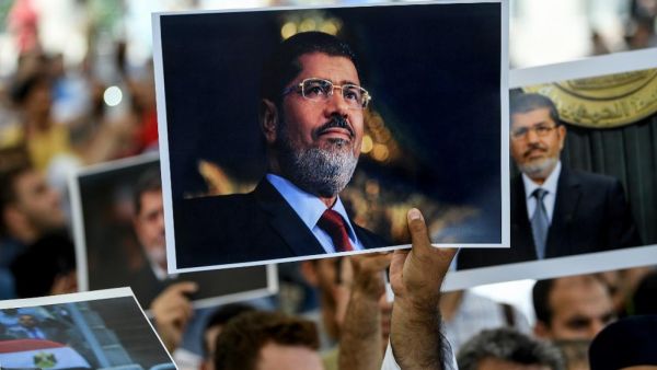 People hold pictures of former Egyptian President Mohamed Morsi during a symbolic funeral ceremony on 18 June in Istanbul (AFP)