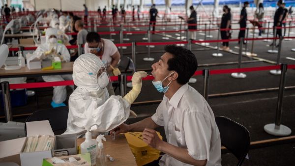 This file photo taken on June 24, 2020 shows a health worker (L, front) wearing a protective suit, face mask and face shield takes a swab test on a man at an outdoor area during a mass testing for the COVID-19 coronavirus at the Jinrong Street testing site in Beijing.NICOLAS ASFOURI / AFP