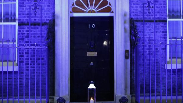 A candle is lit and placed on the doorstep of 10 Downing Street in central London on July 4, 2020 in honour of the tens of thousands of people who have died as a result of the coronavirus pandemic in the UK as the building itself is lit up blue as a tribute to NHS workers and to mark the 72nd anniversary of the NHS. Tolga AKMEN / AFP
