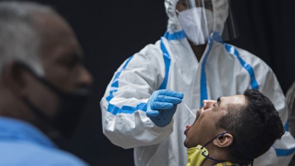 A health official wearing a Personal Protective Equipment (PPE) suit collects a swab sample from a man to test for the COVID-19 coronavirus at a temporary testing facility after authorities eased restrictions imposed as a preventive measure against the spread of the COVID-19 coronavirus, in New Delhi on July 8, 2020. (XAVIER GALIANA / AFP)