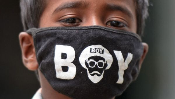 A boy wearing a facemask as a preventive measure against the spread of the COVID-19 coronavirus, looks on near a paddy field in Medak district of Telangana state on July 15, 2020. India joins a raft of countries and cities across the globe to reimpose localised lockdowns and other restrictions in the face of new outbreaks of the disease. Noah SEELAM / AFP