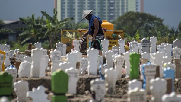 A worker pours water on newly planted flowers at a burial site for victims of the COVID-19 coronavirus at Keputih cemetery in Surabaya, East Java on July 15, 2020. JUNI KRISWANTO / AFP