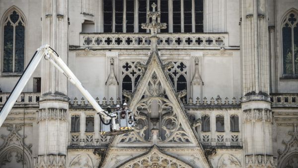 Lifted on a crane, firefighters are at work at the Cathedral of St Peter and St Paul in Nantes on July 18, 2020 after a fire ravaged parts of the gothic building before being brought under control, sparking an arson investigation and leaving Catholic officials lamenting the loss of priceless historical artefacts. The cathedral's 17th century organ was destroyed and its platform was in danger of collapsing, said regional fire chief, but added the damage was not comparable to last year's devastating blaze at 