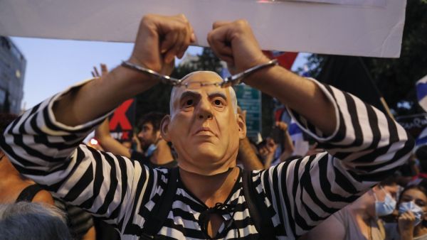 An Israeli protester dressed as a prisoner dons a mask representing Prime Minister Benjamin Netanyahu during an anti-government demonstration outside Netanyahu's official residence in Jerusalem, on July 18, 2020. Ahmad GHARABLI / AFP
