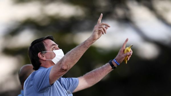 Brazilian President Jair Bolsonaro gestures as he speaks to supporters while holding a banana in his hand in the garden of the Alvorada Palace in Brasilia, on July 24, 2020. EVARISTO SA / AFP