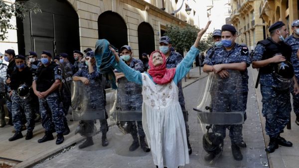 An elderly woman raises her arms in front of Lebanese security forces standing guard in front of the World Bank offices in the downtown district of the Lebanese capital Beirut on July 25, 2020. ANWAR AMRO / AFP
