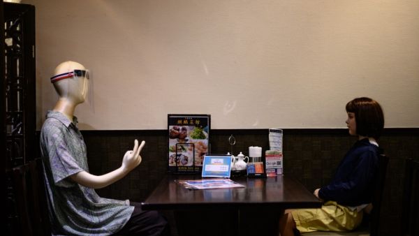 Mannequins, one clad in a face shield and another depicting a child and used as a method to maintain social distancing among diners, are seen seated in a restaurant in the Akabane district of Tokyo on July 26, 2020, amid the COVID-19 coronavirus pandemic. Philip FONG / AFP