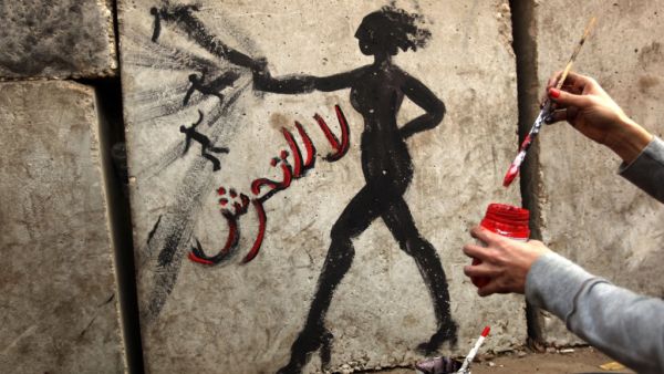 An Egyptian activist draws graffiti depicting a woman and reading in Arabic: “No to Sexual Harassment” on a wall outside the presidential palace in Cairo on December 14, 2012. Photo: PATRICK BAZ / AFP
