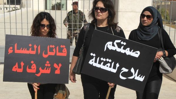 Palestinian women holding placards that read in Arabic, “There is no honour in killing women” (R), and “Your silence is a weapon for their killing”, in a protest against honour killing in the West Bank city of Ramallah, on March 6, 2014. Photo: ABBAS MOMANI / AFP