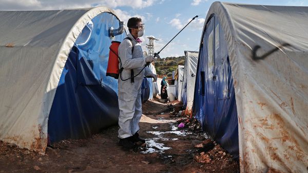 A member of the Syrian relief group Violet Organization disinfects tents at a camp for displaced people north of Idlib, Syria, on March 21. OMAR HAJ KADOUR/AFP VIA GETTY IMAGES