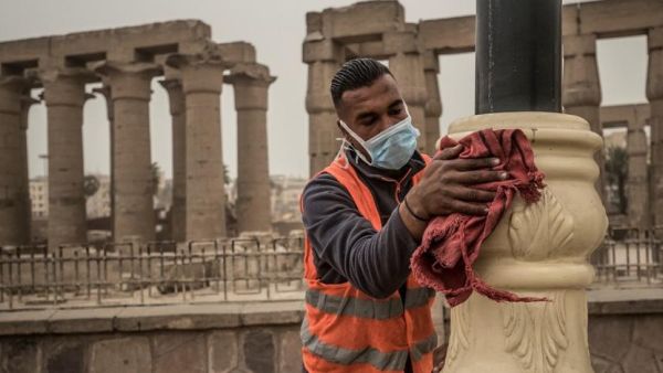 A municipality worker cleans lamp posts amid coronavirus fears outside the Luxor Temple, March 12, 2020. (AFP)