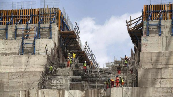 Construction workers stand next to a big rock wall at the Grand Ethiopian Renaissance Dam (GERD), near Guba in Ethiopia. AFP