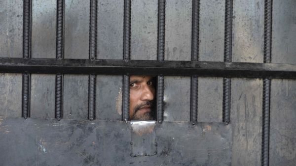 In this picture taken on August 3, 2020, an inmate watches from behind a closed gate after a raid at the prison in Jalalabad. At least 29 people were killed when gunmen attacked a jail in the eastern city of Jalalabad on August 3, shattering the relative calm of the final day of a three-day ceasefire between the Taliban and Afghan forces. NOORULLAH SHIRZADA / AFP