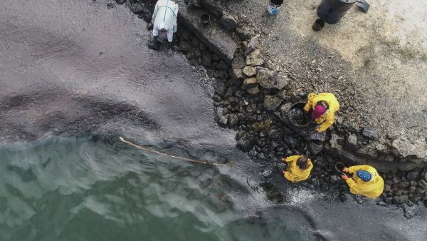 An aerial view shows people scooping leaked oil on August 10, 2020, from the MV Wakashio bulk carrier that had run aground at the beach in Bambous Virieux, southeast Mauritius. L'Express Maurice / AFP