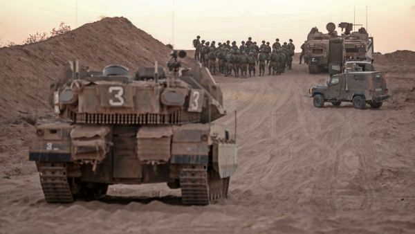 Israeli infantry soldiers gather next to tanks and an armoured personnel carrier near the Israeli border with the Gaza Strip, on August 16, 2020. MENAHEM KAHANA / AFP