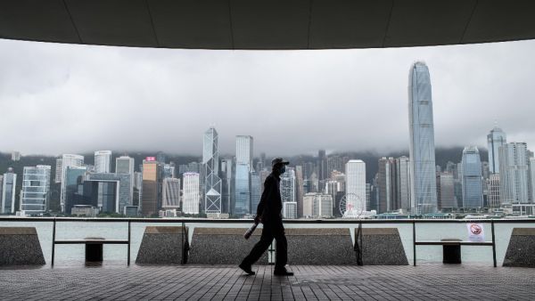 A man walks on Kowloon's Tsim Sha Tsui waterfront that faces Victoria Harbour and the Hong Kong Island skyline (back), after Typhoon Higos swept past overnight in Hong Kong on August 19, 2020. Anthony WALLACE / AFP