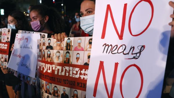 Israeli protesters, wearing protective masks due to the COVID-19 pandemic, hold placards as they take part in a demonstration in Tel Aviv on August 23, 2020, to denounce sexual violence against women. JACK GUEZ / AFP