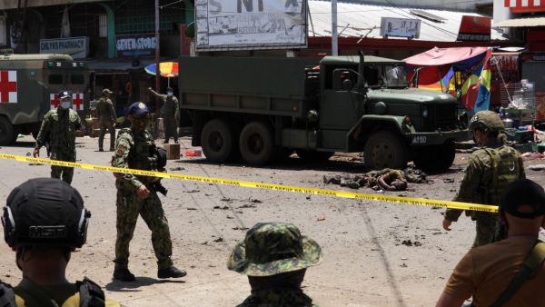 The bodies of victims (C) lie on the pavement as police and military personnel cordon off the site where an improvised bomb exploded next to a military vehicle in the town of Jolo on Sulu island on August 24, 2020. (AFP/File)