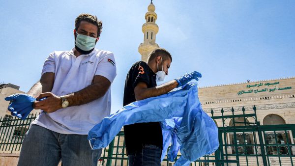 Workers suit up in PPE (personal protective equipment) before sterilizing a mosque in Jordan's capital Amman on June 3, 2020. (AFP)