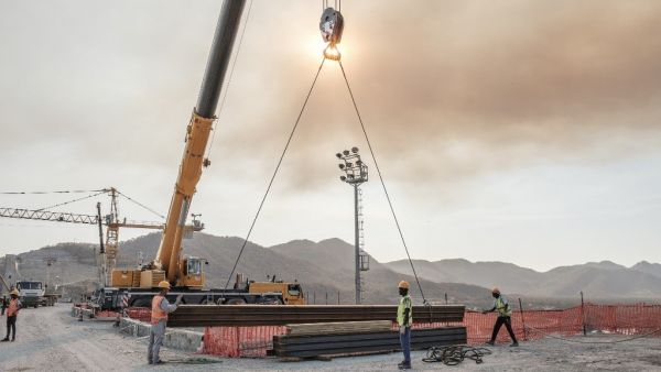 Workers move iron girders from a crane at the GERD on 26 December (AFP)