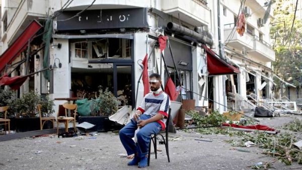 An injured man sits outside a restaurant in the Mar Mikhael area of Lebanon. The port blast ripped through blocks of the city for miles around. (Patrick Baz/AFP/Getty)