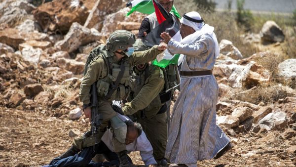 An Israeli soldier, mask-clad due to the COVID-19 coronavirus pandemic, scuffles with Palestinian protesters near the village of Shoufah, southeast of Tulkarm in the occupied West Bank on August 20, 2020, amidst a protest against the clearing of lands to expand Israeli settlements. JAAFAR ASHTIYEH / AFP