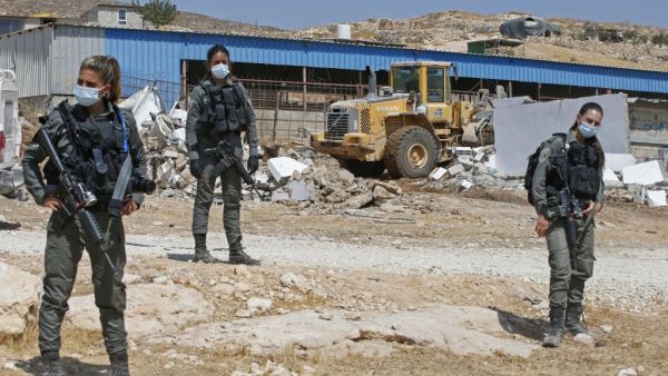 Israeli security forces guard a bulldozer demolishing a Palestinian house and shack in the southern West Bank village of Khirbet Jinba on September 1, 2020. (AFP)