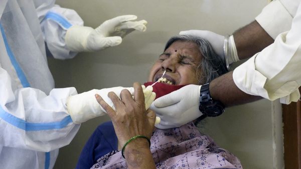 A health worker (L) wearing a Personal Protective Equipment (PPE) suit collects a swab sample from a woman to test for the Covid-19 coronavirus at a primary health centre in Hyderabad on September 3, 2020. NOAH SEELAM / AFP