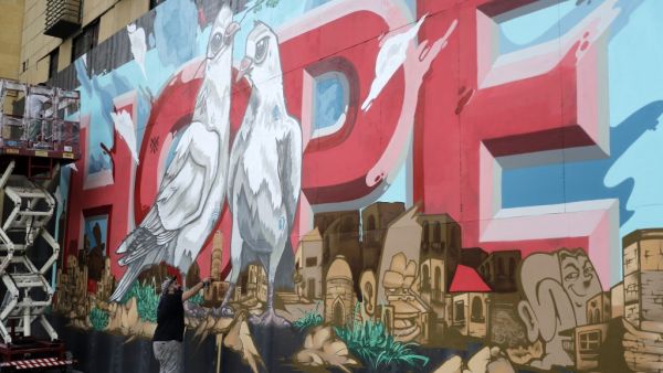 Artists from the group REK paint a mural on a barrier erected in front of Le Grey hotel in Beirut's downtown district, depicting the city with the word "HOPE" inscribed on it, on September 4, 2020, one month after the August 4 massive blast at the nearby seaport that left scores of people dead or injured ravaged swaths of the Lebanese capital. JOSEPH EID / AFP