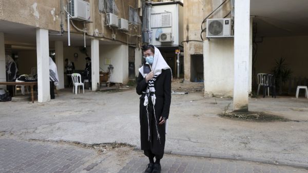 Ultra-Orthodox Jewish men, wearing a protective face masks due to the COVID-19 coronavirus pandemic and "Talit" prayer shawl, keep a two-metre distance as they pray along a street outside a synagogue in the ultra-Orthodox city of Bnei Brak, near Tel Aviv on September 6, 2020. Israel, next week, is expected to impose a new lockdown over some ten cities following the spread of the Coronavirus disease. MENAHEM KAHANA / AFP