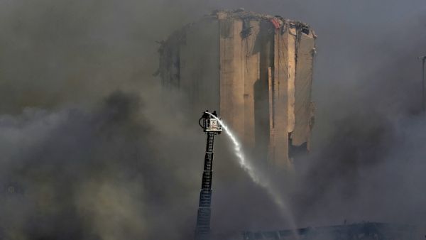 Lebanese firefighters stand on a ladder amid billowing smoke as they extinguish the remaining flames at the seaport of Beirut, on September 11, 2020, a day after a huge fire erupted in harbour warehouses. ANWAR AMRO / AFP