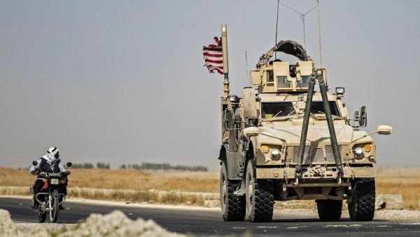 A Syrian man rides a motorcycle past a US military vehicle patrolling the town of Tal Tamr, in Syria's northeastern Hasakeh province, on September 21, 2020. Delil SOULEIMAN / AFP