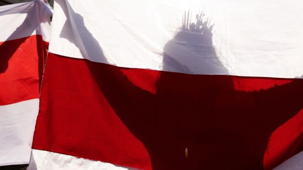 A woman carries a former white-red-white flag of Belarus as she parades through the streets during an opposition rally to protest against the presidential inauguration in Minsk on September 26, 2020. Belarus leader Alexander Lukashenko held his presidential inauguration in secret on September 23, 2020, after claiming victory in disputed polls that his opposition rivals have described as massively rigged. STRINGER / AFP
