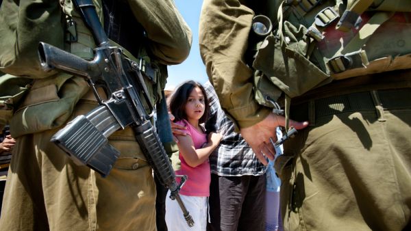 A Palestinian girl faces Israeli soldiers (Shutterstock)	
