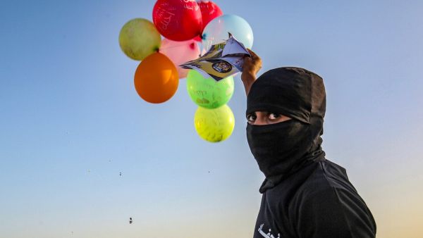 Masked Palestinians of the Popular Resistance Committees prepare to release balloons carrying slogans towards Israel, near Rafah, along the southern border between the Gaza Strip and Israel, on September 28, 2020 on the 21st anniversary of the group. SAID KHATIB / AFP