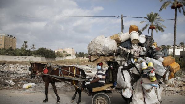A Palestinian man collects plastic containers on his horse cart while wearing a protective mask due to the COVID-19 coronavirus in Deir al-Balah in the central of Gaza Strip on October 1, 2020. MOHAMMED ABED / AFP